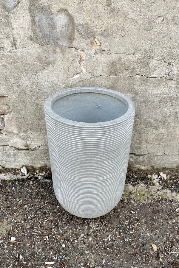 The small light grey High Cody Ridged pot shown against a grey concrete wall from the above and side.