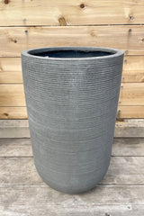 Detail of Cody High Pot horizontal ridged dark grey large against a wooden fence