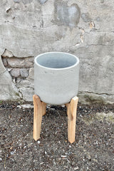 The grey washed extra large part pot with high stand against a concrete wall. 