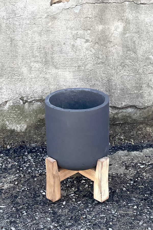 A full view of Charlie Pot & low stand black washed medium against concrete backdrop