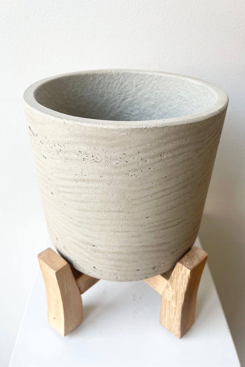 Detail of the top of the Charlie Pot & low stand grey washed medium against a white wall 