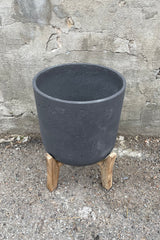 Detail of the top of Charlie Pot & low stand black washed extra extra large against a grey wall