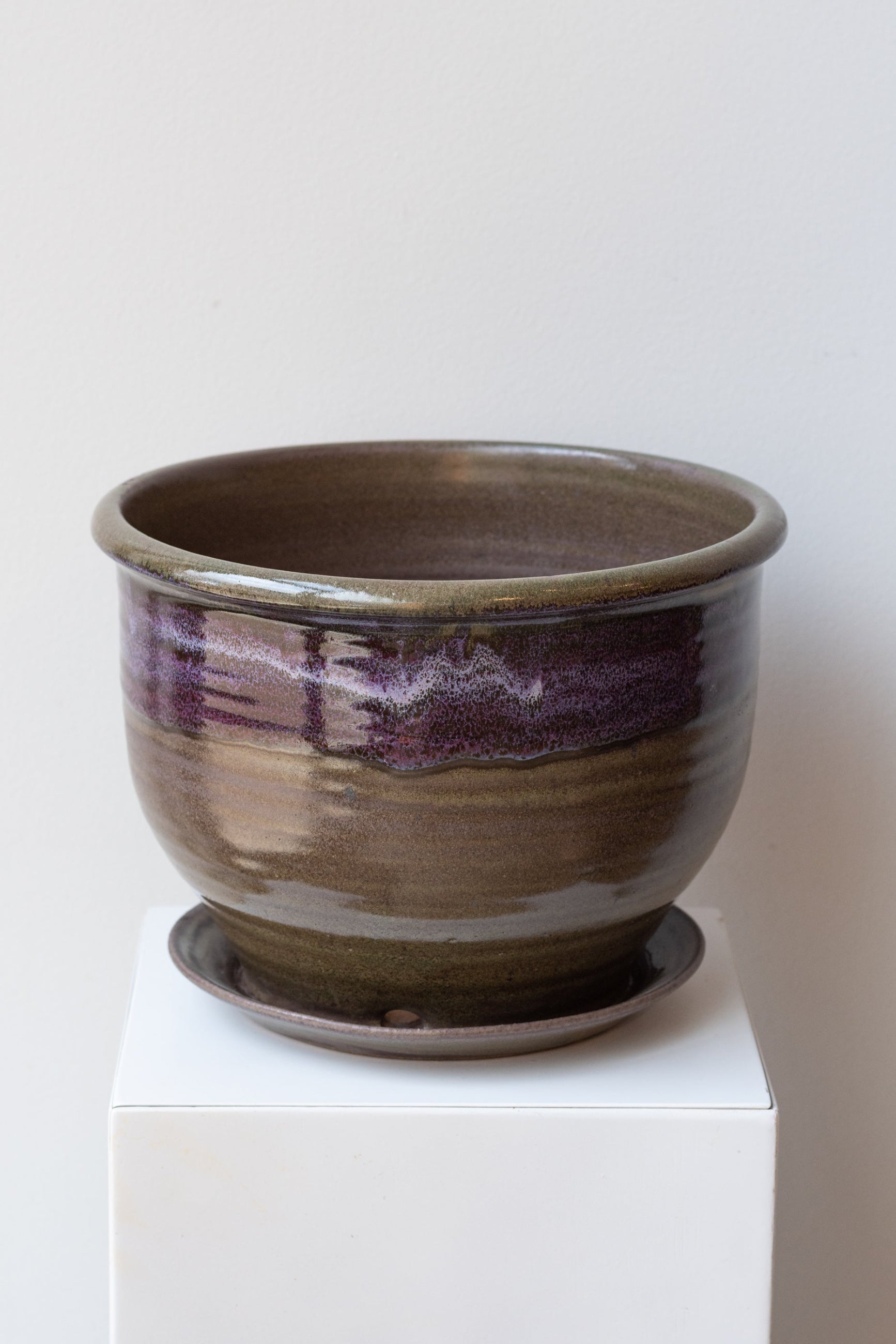 A round ceramic planter with a moss and lilac glaze, displayed on a white pedestal. ©Sprout Home