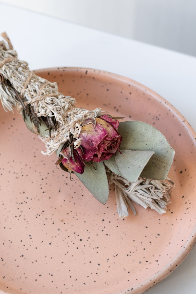 Close up of Apricot Pastel Snack Plate by Christina Kosinski with rose and eucalyptus smudge stick