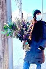 A woman outside holds Plum Fizz Preserved floral arrangement by Sprout Home 