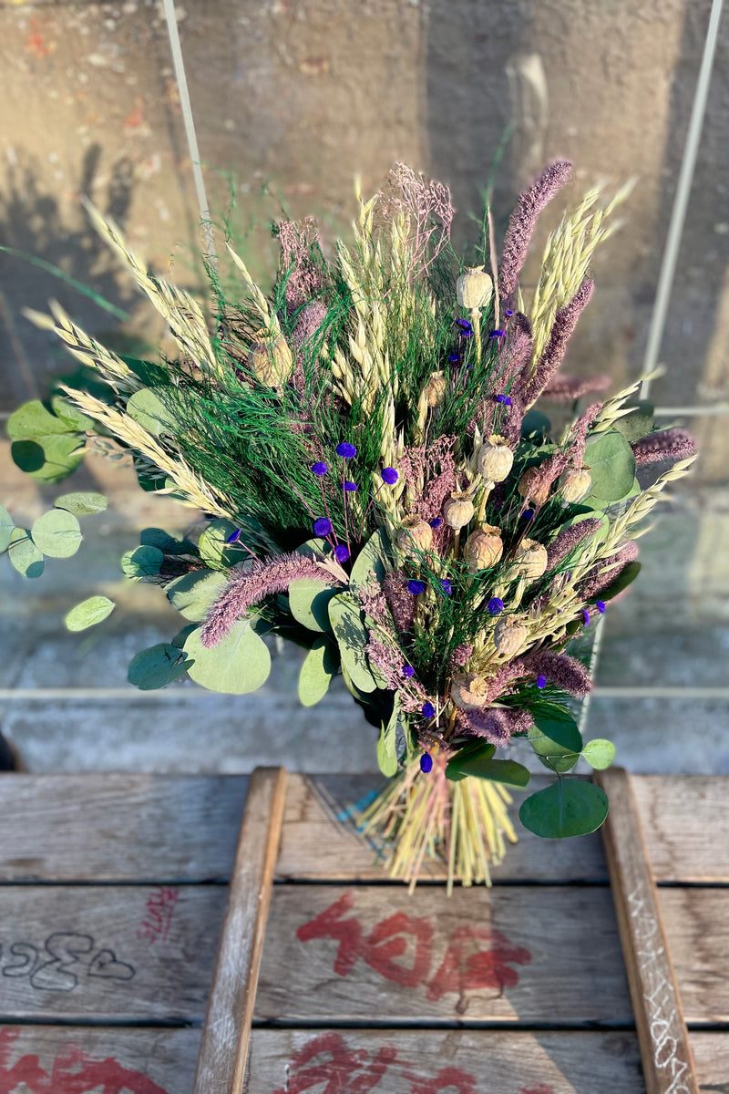 Plum Fizz Preserved floral arrangement by Sprout Home sits on a bus bench
