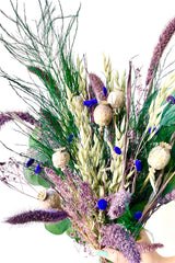 A close-up view of Plum Fizz Preserved floral arrangement by Sprout Home held by hand against a white backdrop