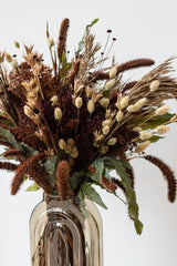 Close up of "Allspice" autumnal preserved floral arrangement by Sprout Home in grey retro glass vase in front of white background