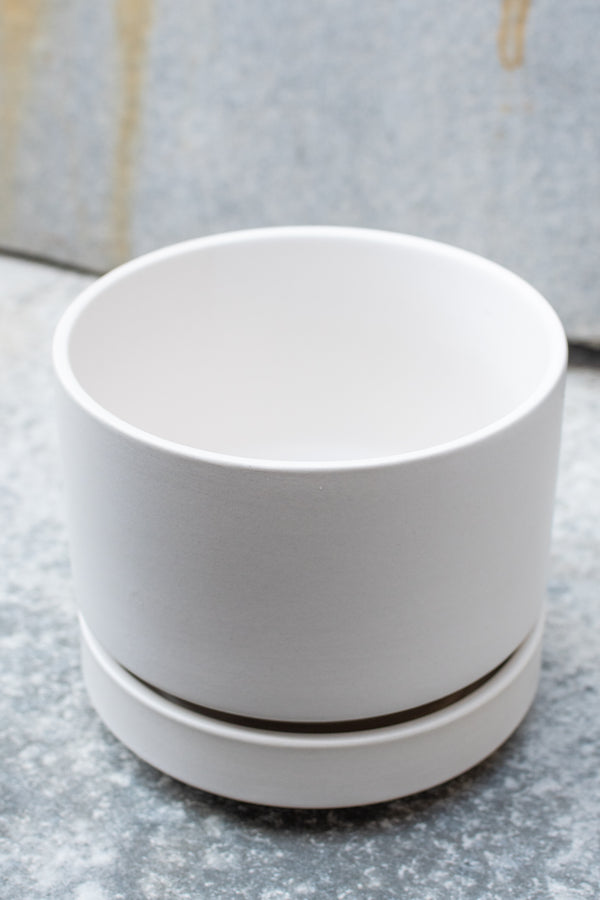 White stoneware planter with matching saucer by LBE Designs sits in front of a grey background