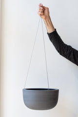 Angus and Celeste Raw Earth Hanging Planter charcoal large held in front of white wall
