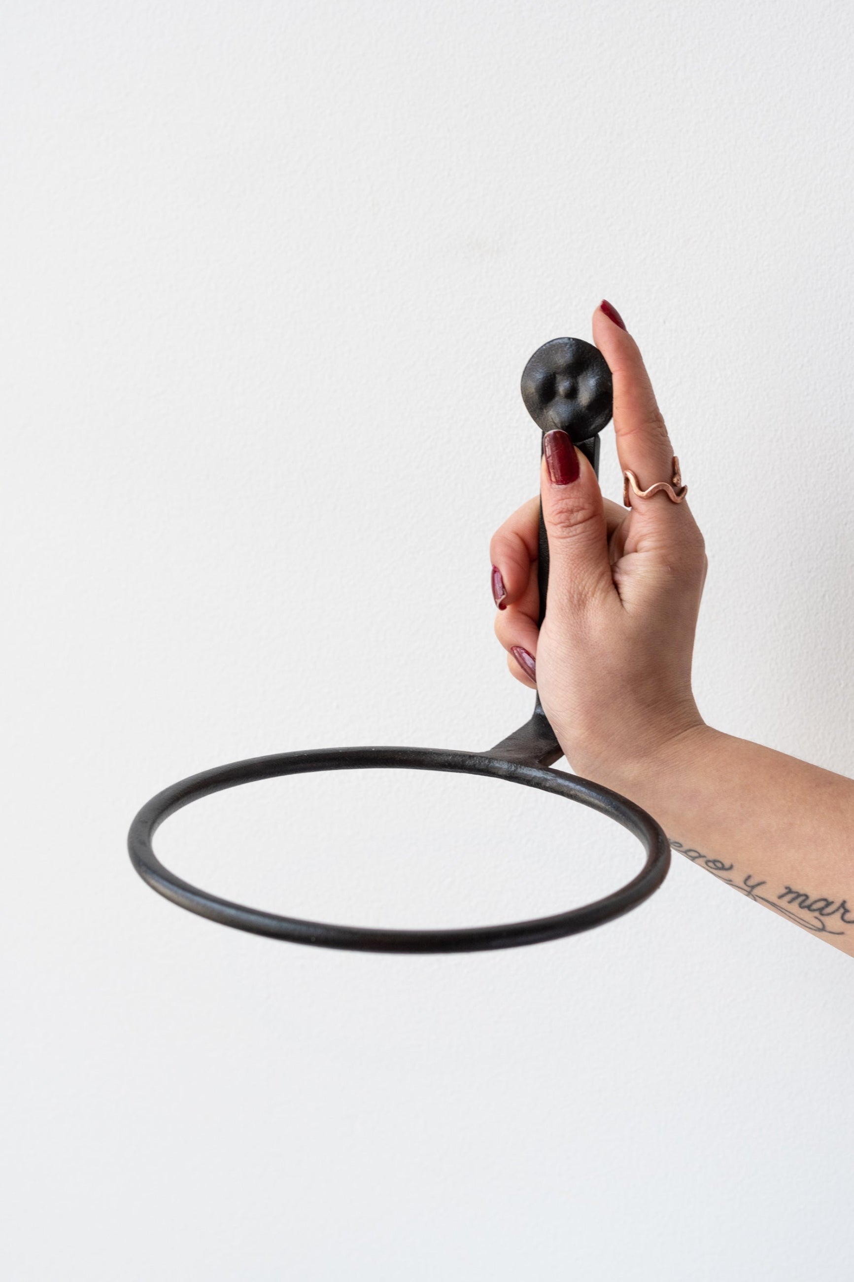 Tattooed arm with red nails holding 6 inch black flowerpot ring by Achla