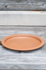 10" clay metal plant saucer on a grey wood surface