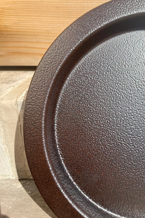 A detailed view of the 13" Saucer in textured copper against a wood backdrop