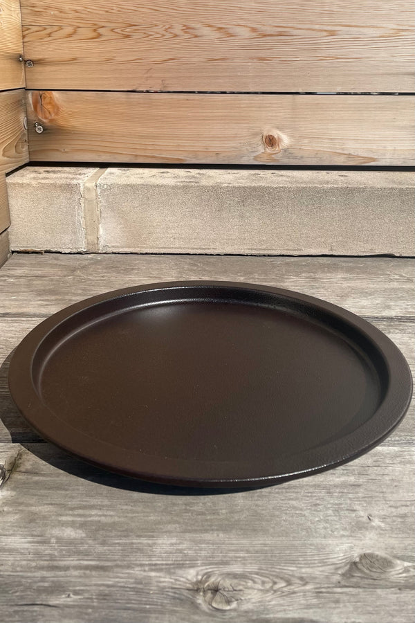 A slight overhead view of the 13" Saucer in textured copper against a wood backdrop