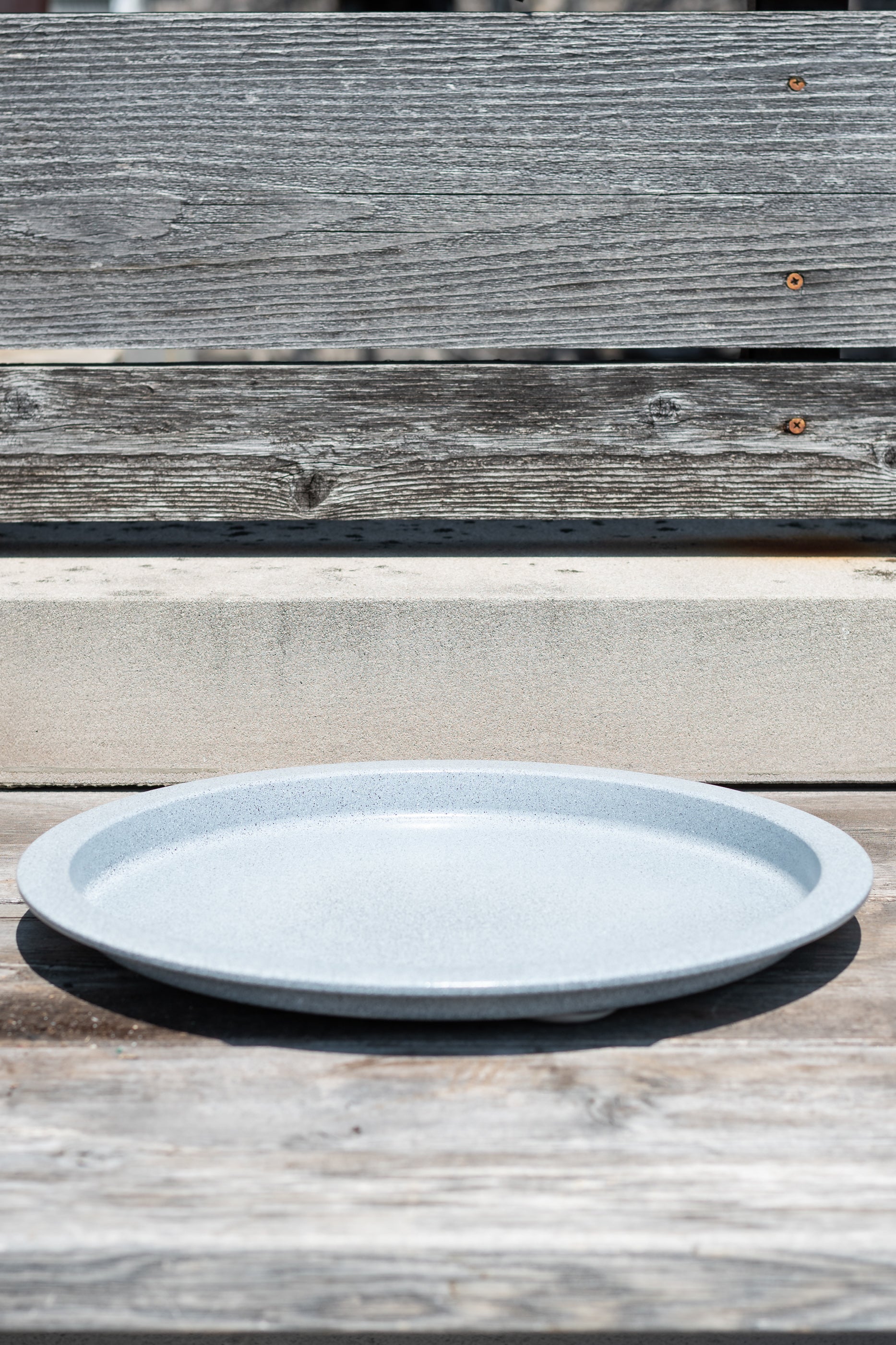 15" multi granite metal plant saucer on a grey wood surface