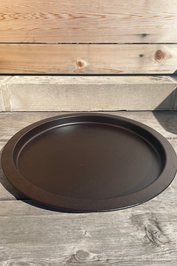 A slight overhead view of the 15" Saucer in textured copper against a wood backdrop