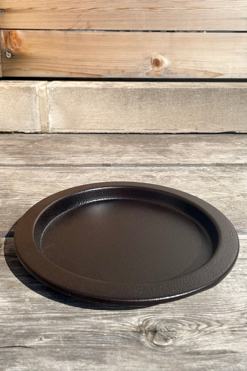 A slight overhead view of the 8" Saucer in textured copper against a wood backdrop