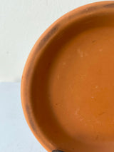 detail of Clay Standard Saucer Terracotta 4.3" against a white wall
