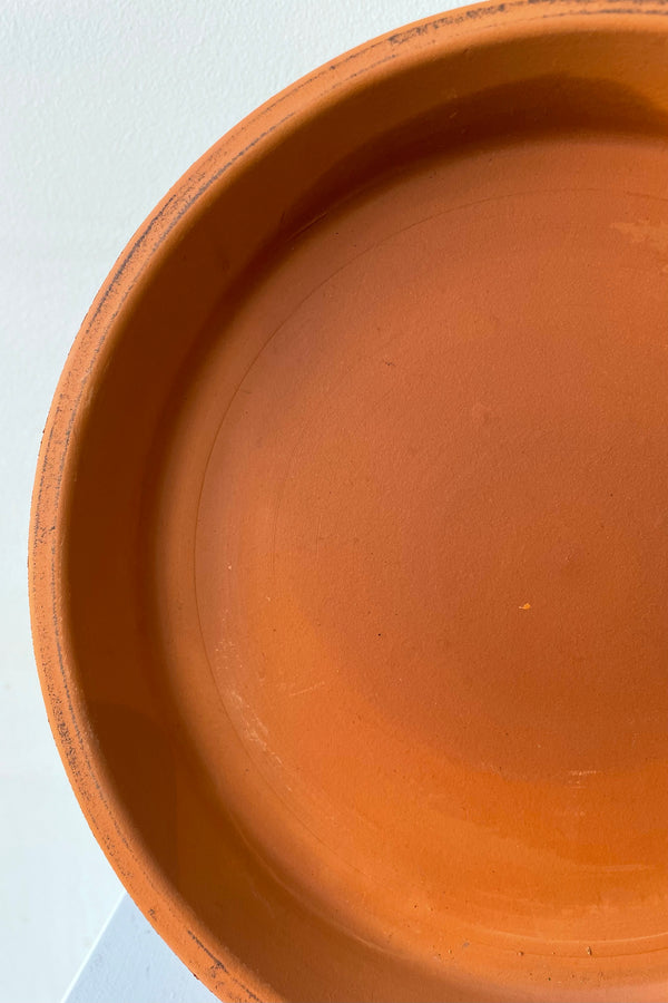 Detail of Clay Standard Saucer Terracotta 9.1" against a white wall