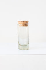 Small corked glass spice jar on a white surface in a white room