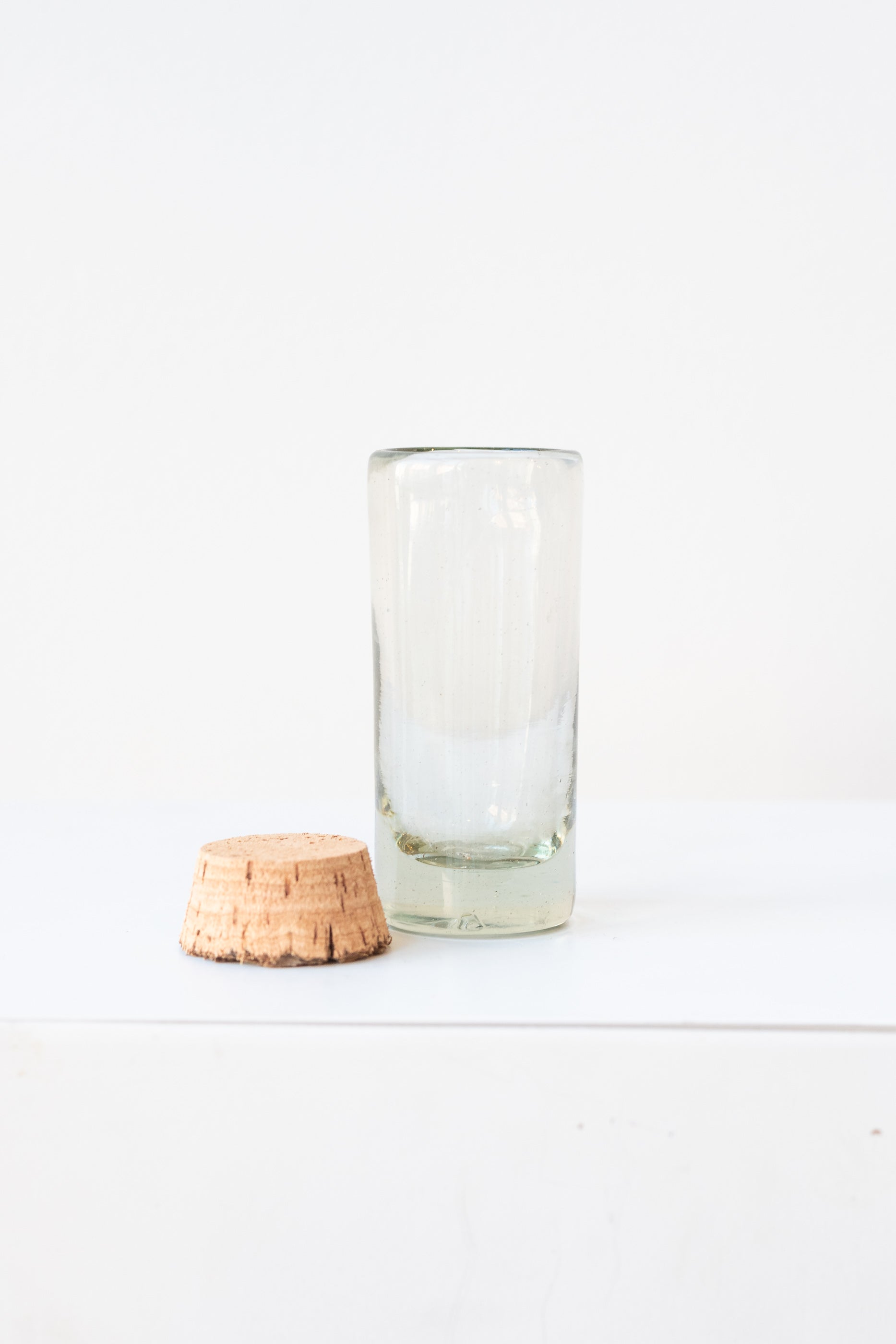 Small corked glass spice jar on a white surface in a white room