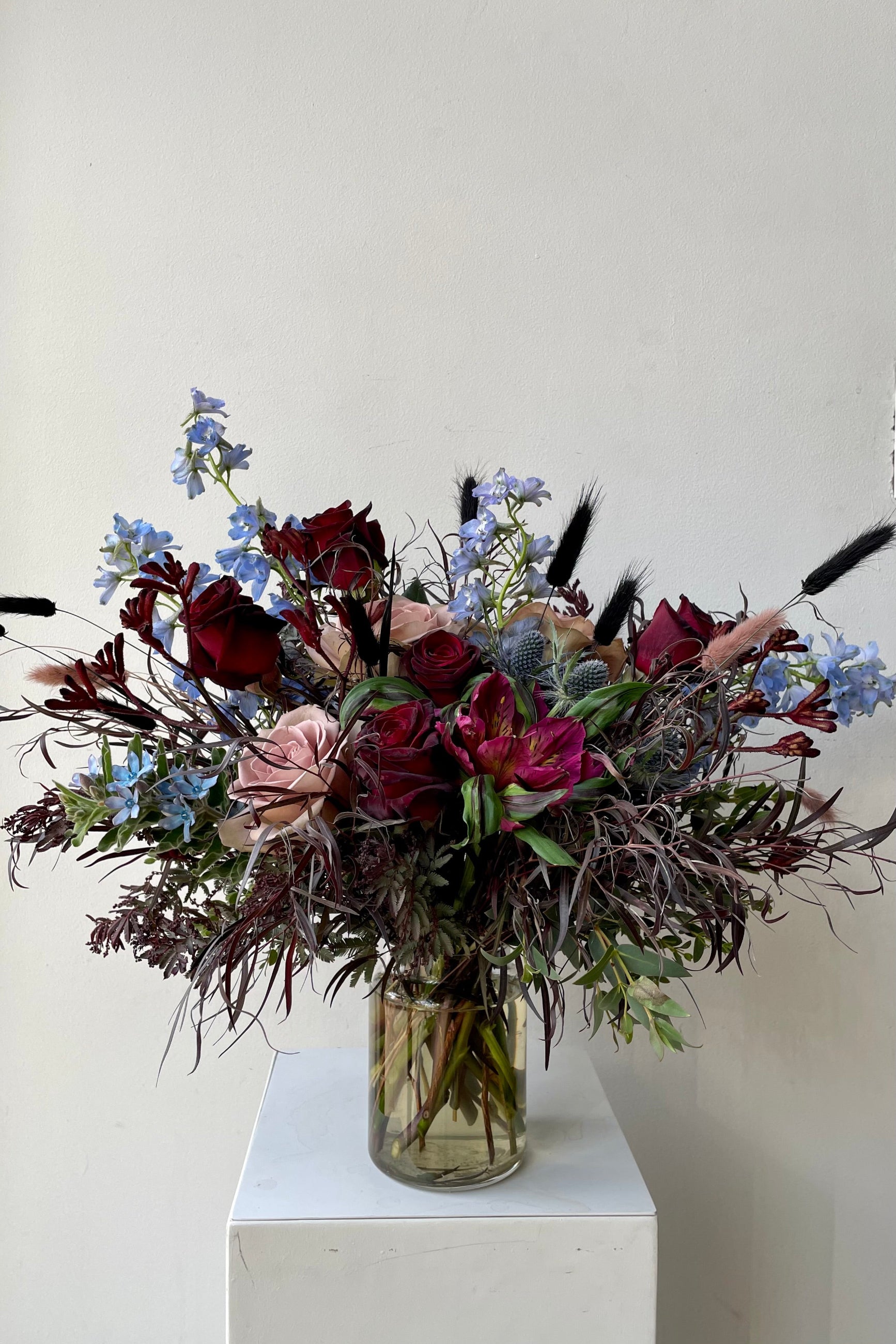 An example of fresh Floral Arrangement Storm with burgundy foliage and blue delphinium from Sprout Home Floral in Chicago  ©Sprout Home #size_$130