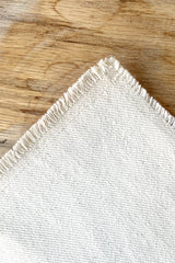 A detailed view of the white Raw Denim Placemat against a wood background