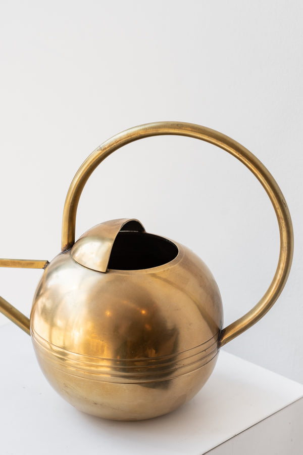 Close up of round handle on round brass watering can.