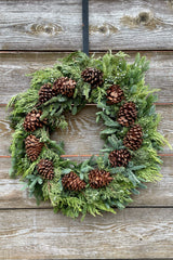 Multicone deluxe wreath 24" diameter hanging on a wood fence.