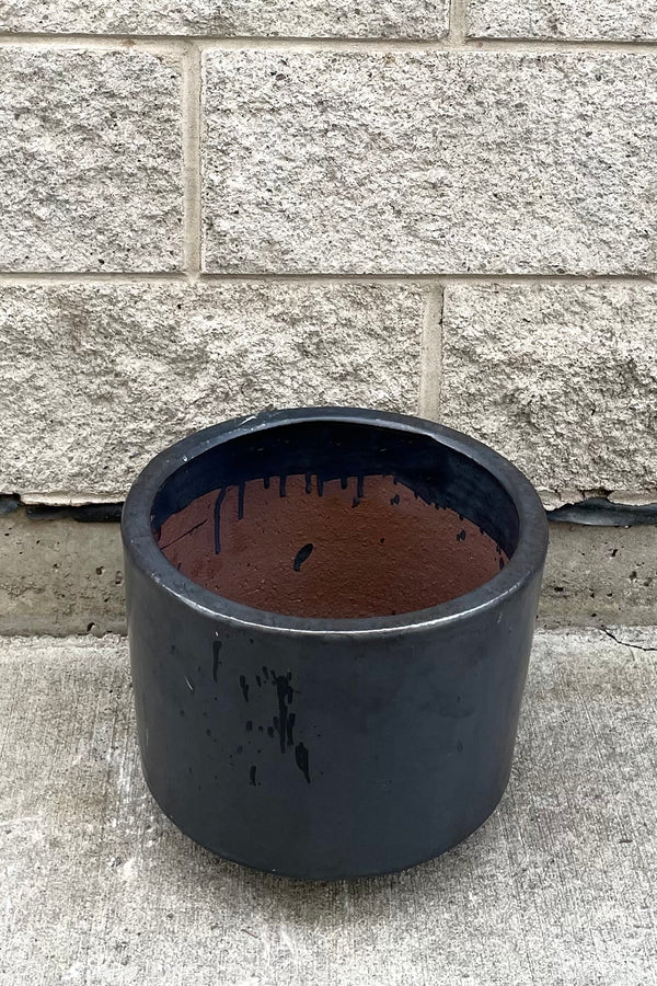 A slightly overhead view of Lara Graphite Planter Small against concrete backdrop