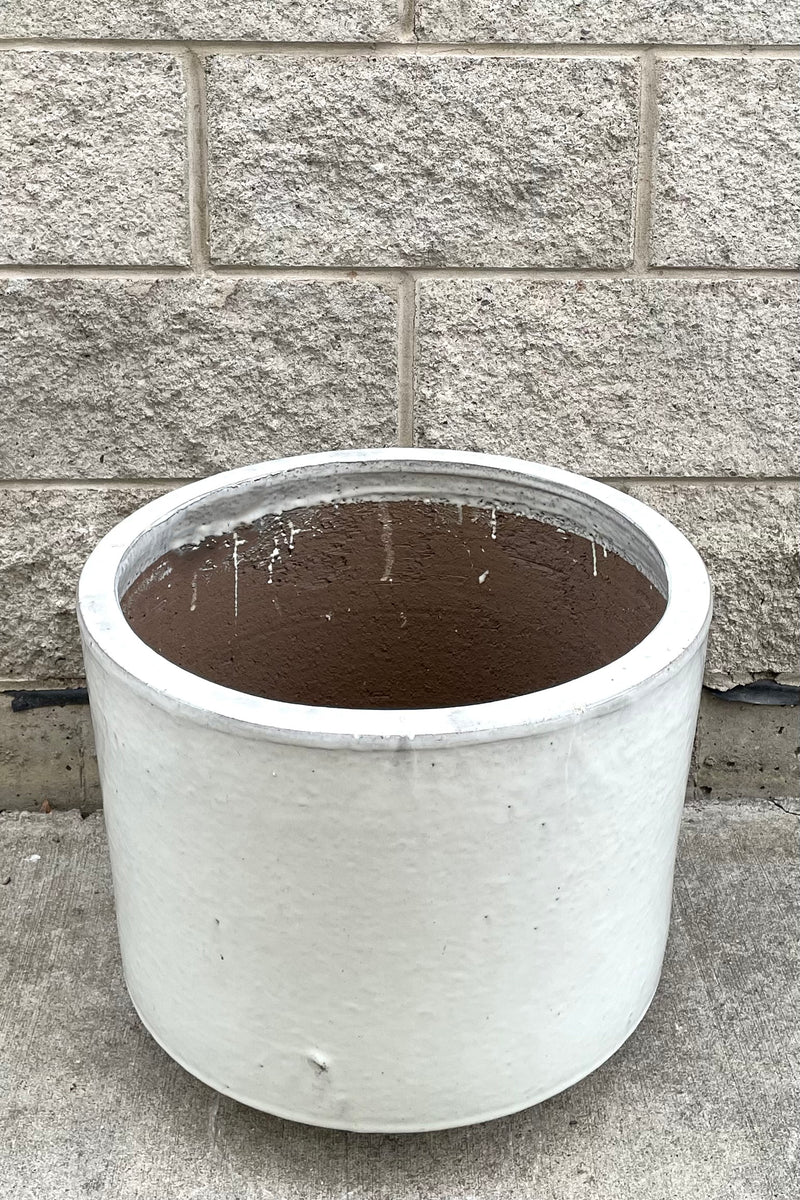 A slightly overhead view of Lara Oyster White Planter Large against concrete backdrop