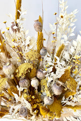 Textured dried floral arrangement that reaches and moves through the image. Vibrant colors of yellow, white and tan .