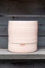 Self-Watering Plant Pot burnt coral tall by Angus and Celeste in front of grey wood background