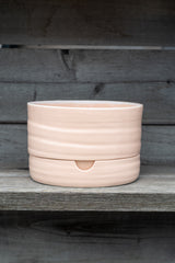 Self-Watering Plant Pot burnt coral by Angus and Celeste in front of a grey wood background